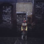 Artist Chen Qiulin dressing the traditional opera costumes stands in front of a wall.