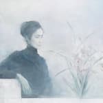 A young lady in black cloth sits on a white chair looking towards the right and viewing the flowers