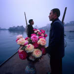 Two Bang Bang men and two vases of flowers are on the boat.