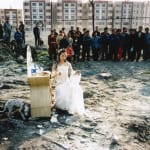 A fair maiden in white long skirt sits in the center of ruins and is surrounded by the crowds