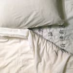 A closer shot of bed in white sheet from the living room of village women in Guizhou