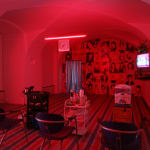 A barber shop is relocated into a room with pinkish lights and there's an old-fashioned TV hanging on the right wall in 2006.