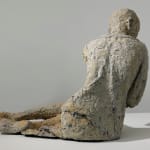 The back of a reclining woman who is made of paper mache.