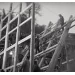 A black-and-white triptych photograph from the section "At Dawn" of Chen Qiulin's work "Another Day" where shows a group of village workers working on a huge wooden building structure.
