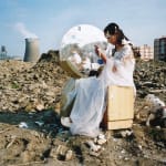 A fair maiden in white long skirt sits in front of a dressing table on the ruins