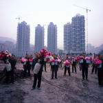 A group of Bang Bang men holding the vases of flowers respectively with the background of newly built residential communities.