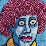 embroidery showing woman with red hair asking "what am I doing and how did I get here"