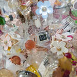 Detail photo of “Fantasy Of Love”, sculpture by Sandra Sashou artist from Brazil, based in London. Available at Carousel Fine Art Miami. The artist’s technique features antique, vintage, and contemporary perfume bottles, crystal glass, silver, and porcelain as her signature materials. The destruction of these precious objects implies tragedy, but their reassembly symbolizes rebirth. Shashou sees breakage and fractures as part of fate, reflecting the personal history of human life. Colors of this work of: Pink, Magenta, Green, Blue, Yellow, Orange, Purple, Silver, Gold, Brown, Grey, White, Black