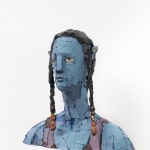 Image of the sculpture: bust of a blue-skinned and yellow-eyed Avatar-character with dark-haired braids adorned with orange beads. Photographed from left side.