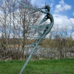 A monumental bronze sculpture of a winged female stands in front of trees at a Dorset sculpture park, Sculpture by the Lakes