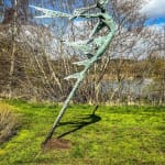 A monumental bronze sculpture of a winged female stands in front of trees at a Dorset sculpture park, Sculpture by the Lakes