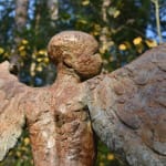 Detail of back of head and wings of Bronze resin sculpture of mythical Greek winged figure Icarus by Nicola Godden, displayed on integral stone plinth