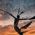 #A monumental bronze sculpture of a winged female by Nicola Godden stands in front of a sunset at a Dorset sculpture park, Sculpture by the Lakes