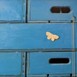 Painting of stacked crates and an apple with a bucket of paint