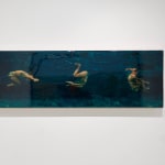 Three swimmers tumbling in dark blue water