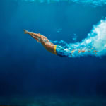 Oil painting of male swimmer in vast blue water on canvas