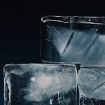 Detail of large ice cubes stacked in a pyramid with blue background