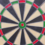 Painting of a realist dart board with missed darts in the wall surrounding it