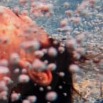 Woman's face blowing bubbles underwater