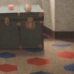 Image of a green trunk in a room filled with sunlight and a red, blue and white floor