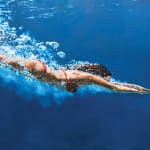 Woman in a red bikini diving through blue water