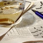 Photorealistic painting of pen, crossword puzzles, and glass of white wine