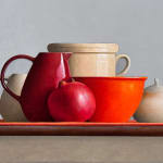 Still lIfe painting with white and red vessels and a pomegranate