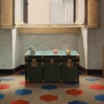 Image of a green trunk in a room filled with sunlight and a red, blue and white floor