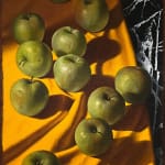Green apples on orange table cloth with black marble poking out