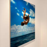 Man in bathing suit doing a cannon ball dive through the air above water