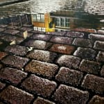 Painting of paved street with a puddle and reflection