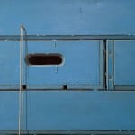Painting of stacked crates and an apple with a bucket of paint