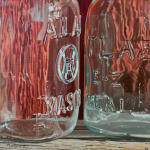Painting of glass mason jars on a wood table in front of a red wall