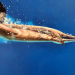 Woman in a red bikini diving through blue water