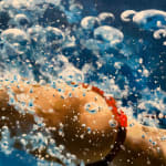 Woman in a red bikini diving through blue water