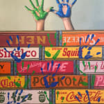 Painted hands above boxes in blue and green with prints all over boxes