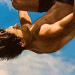 Man in bathing suit doing a cannon ball dive through the air above water