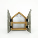 Wooden cabinet shaped like a house with metal cast on the front