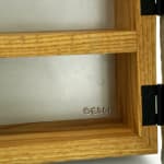 Wooden cabinet shaped like a house with metal cast on the front