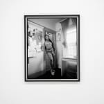 black and white photo of a woman standing in the doorway of her apartment