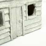 Wooden cabinet shaped like a house with metal cast on the front