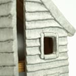 Wooden cabinet shaped like a house with metal cast on the front