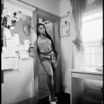 black and white photo of a woman standing in the doorway of her apartment