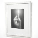 black and white charcoal hand holding a lit match, framed in white