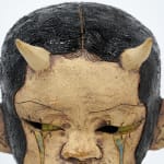 ceramic bust of a person with long hair and horns