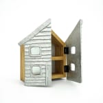 Wooden cabinet shaped like a house with metal cast on the front