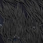 small ceramic needles sewn to a dark indigo canvas