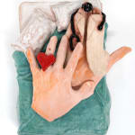 ceramic sculpture of a hand laying in a bed