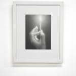 black and white charcoal hand holding a lit match, framed in white