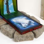 triptych painting positioned on top of a bed of rocks by Mia Scarpa. The artwork represents the tree of life